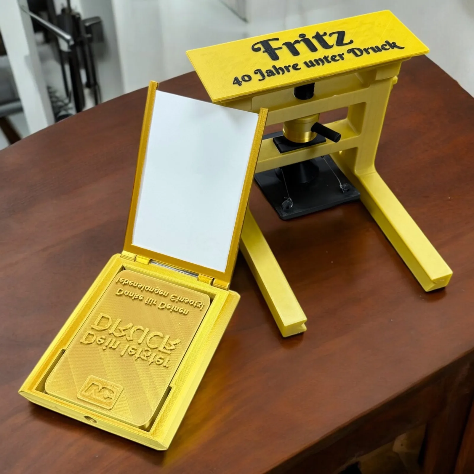Funktionsfähige 3D gedruckte Mini-Offset-Druckpresse in Gelb mit Press-Mechanismus, Widmung ‚Fritz — 40 Jahre unter Druck' — Abschiedsgeschenk für langjährigen Drucker-Mitarbeiter, sofortdruck.at Wien