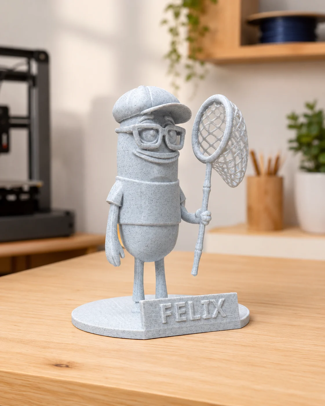 3D gedruckte Felix-Figur mit Schiebermütze, Brille und Kescher auf Sockel mit Schriftzug FELIX — Andenken an einen langjährigen Freund