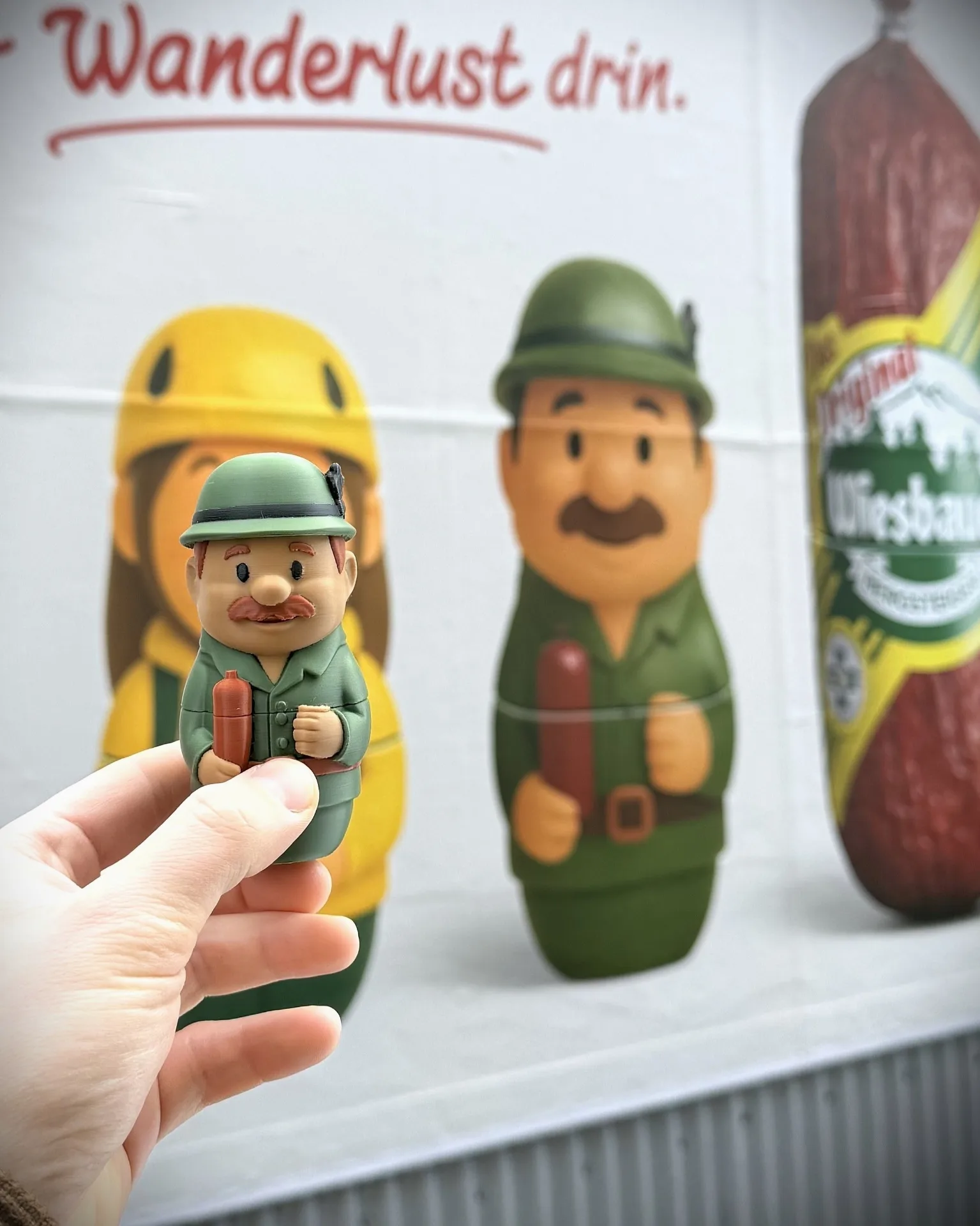 Custom 3D-gedruckte Wiesbauer-Sammelfigur mit Handbemalung vor passendem Wiener Wandbild — B2B Prototyp & Produktentwicklung aus 1080 Wien, sofortdruck.at